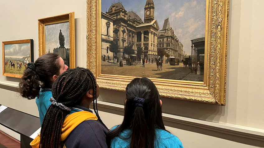 Three young school children looking up at painting of Melbourne Town Hall