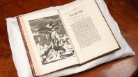 Image of opened rare edition of John Milton, Paradise lost, London, 1688 (first illustrated edition). The volume is placed on a white pillow on a brown table. On the left hand page is an illustration; on the right is the first page with headings stating Paradise Lost, Book 1.