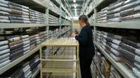 A woman standing in a row of tall shelves