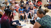 two women presenting a book reading to seated children