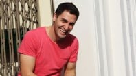 Smiling man with dark hair wearing a red T-shirt