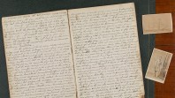 An old handwritten diary lays open beside photos of a US Confederate soldier and a clipper ship