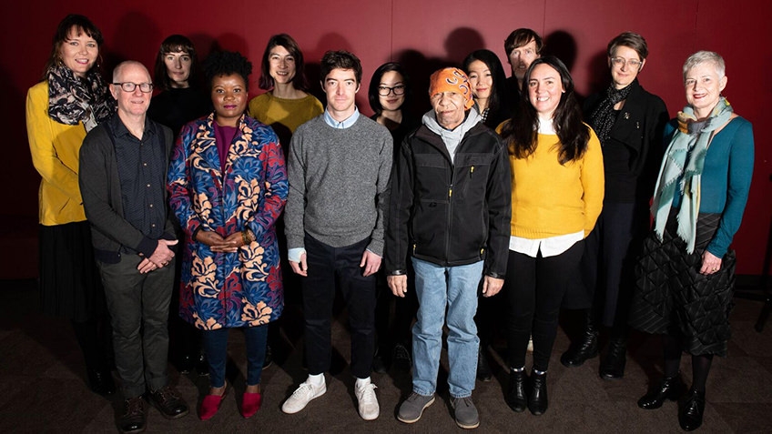 group shot of men and women against red background
