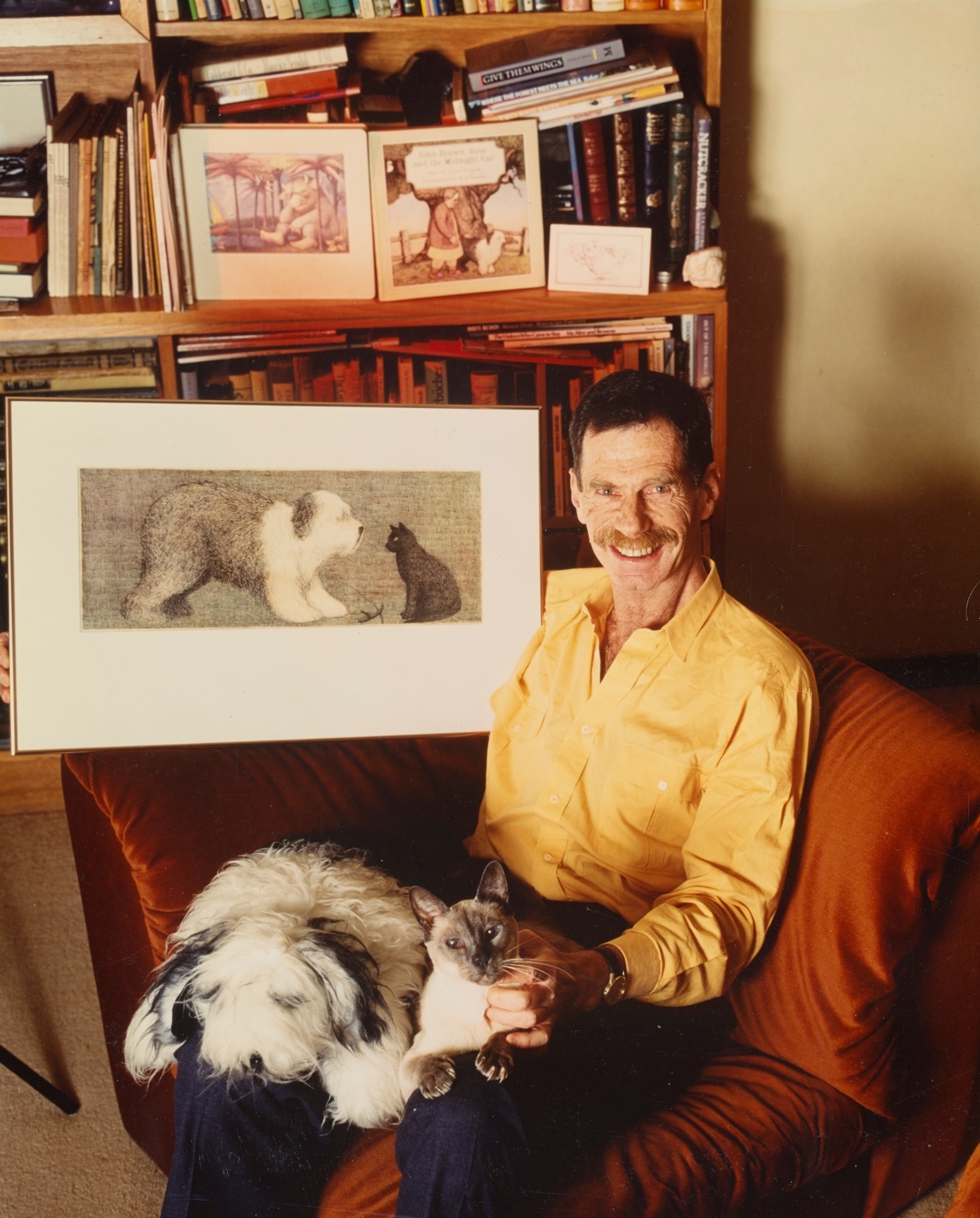 A smiling man sits with a fluffy dog on his lap