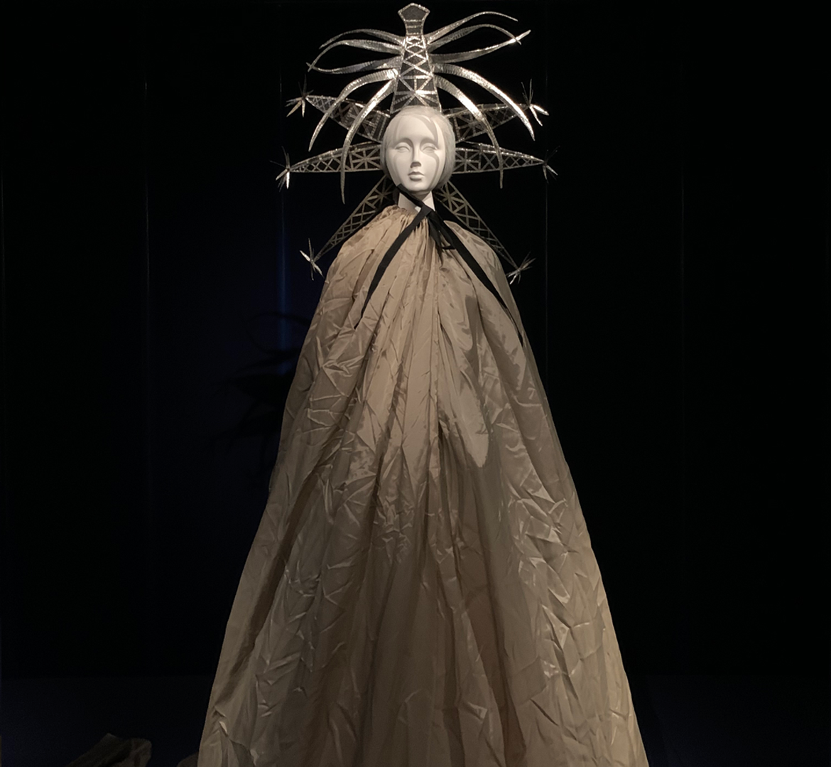 A mannequin wears a striking headress and a floor-length cloak