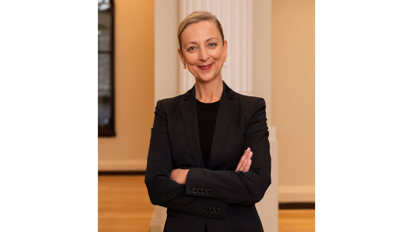 Woman in black suit smiling with her arms crossed