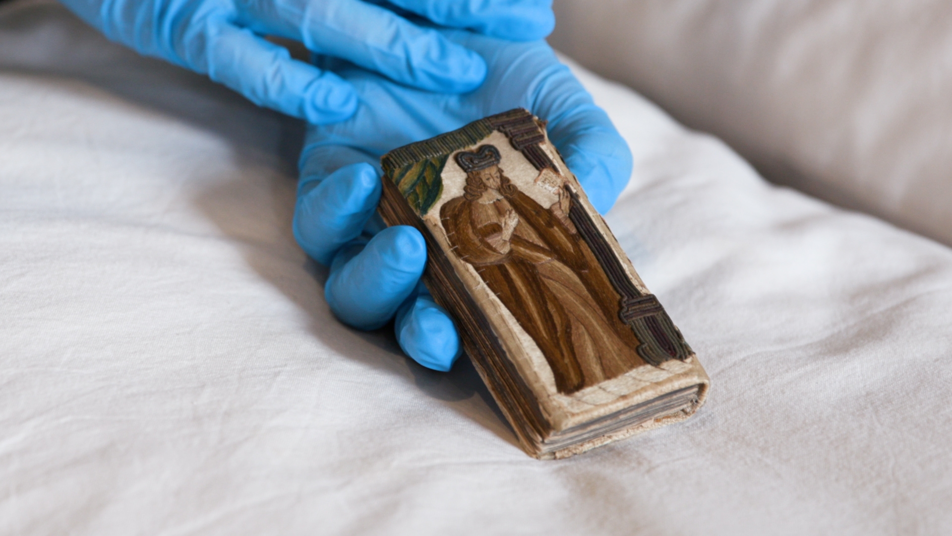 Gloved hands holding a small book