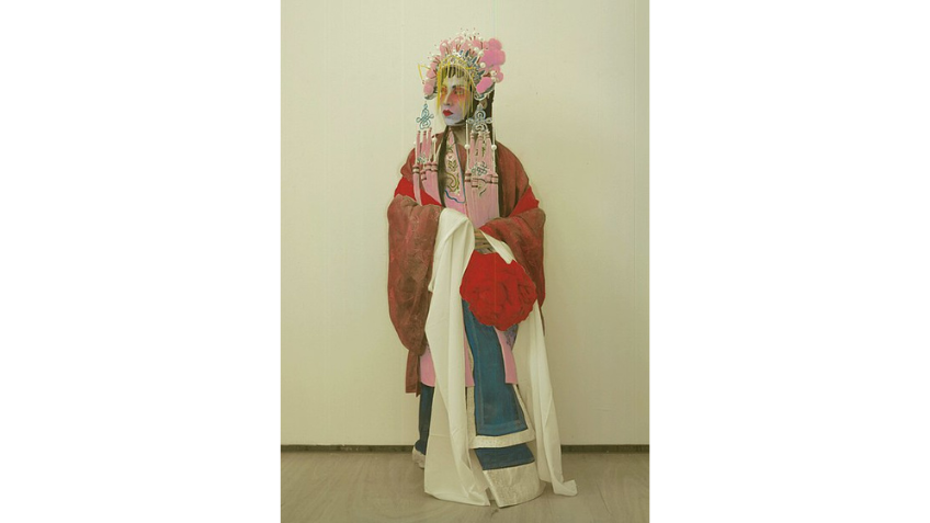 Hand coloured photo of a Cantonese Opera Male Dan performer as Hau Mulan in 1927, Hong Kong. In the exhibition artist Scotty So playfully challenges the truthfulness of photography and archives, blending beauty, history and illusion to explore identity, queerness, and the power of belief. Source State Library Victoria 