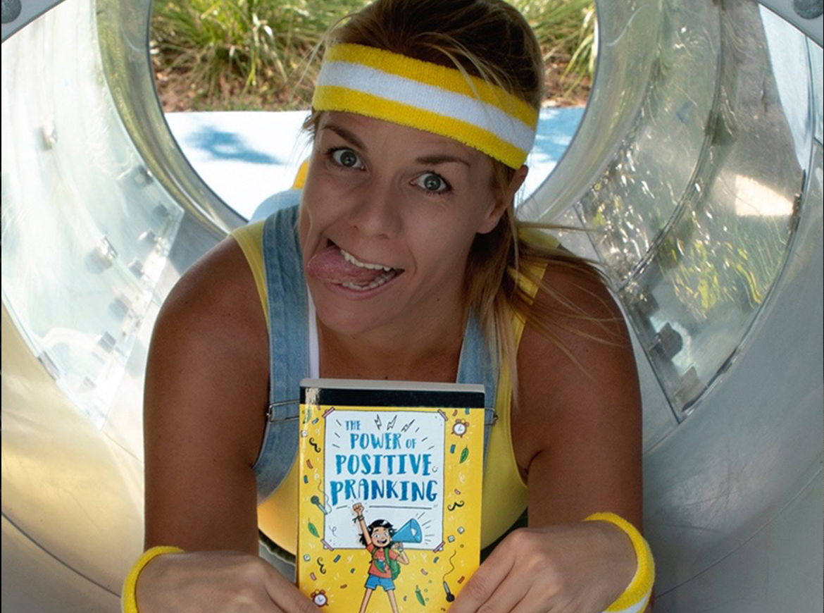 A woman in a yellow sweatband makes a funny face while laying on her tummy