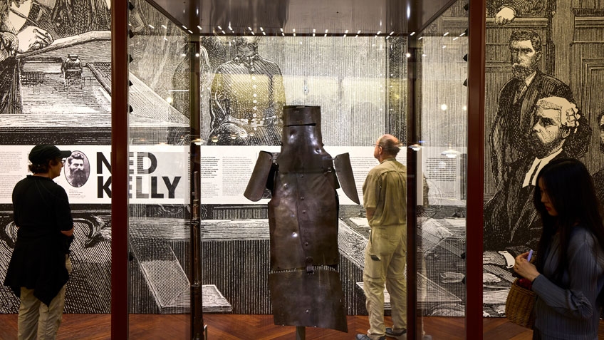 View of Ned Kelly armour on display in the Redmond Barry Reading Room. The armour is in a glass case.