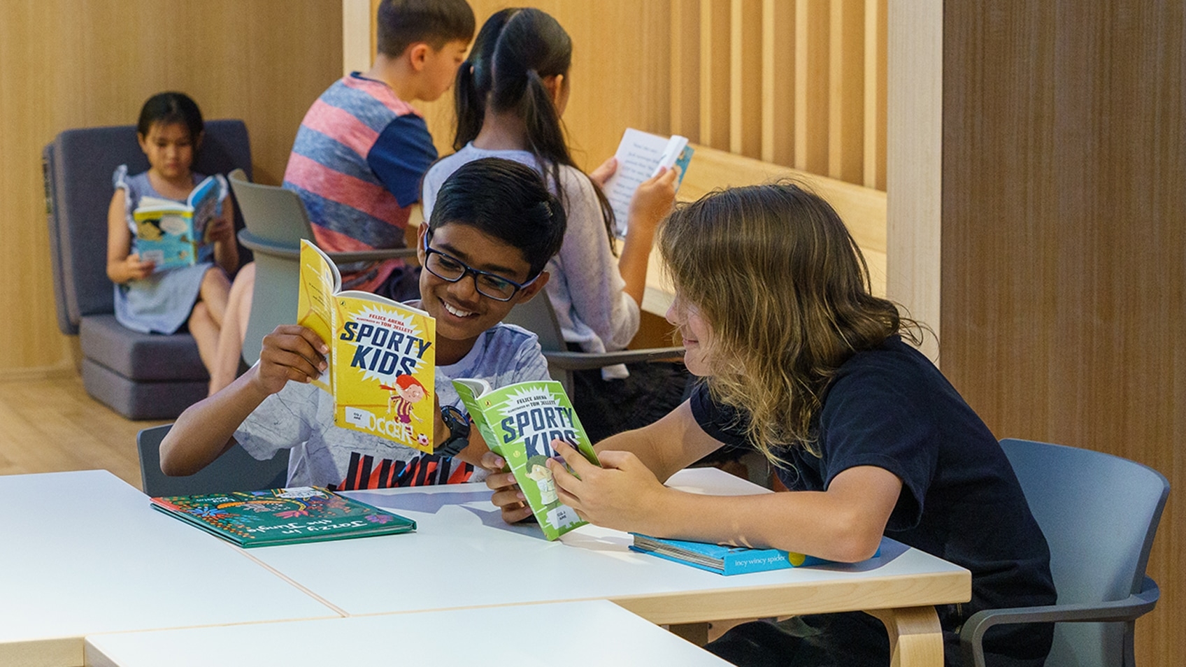 two boys reading sporty kids books at a table