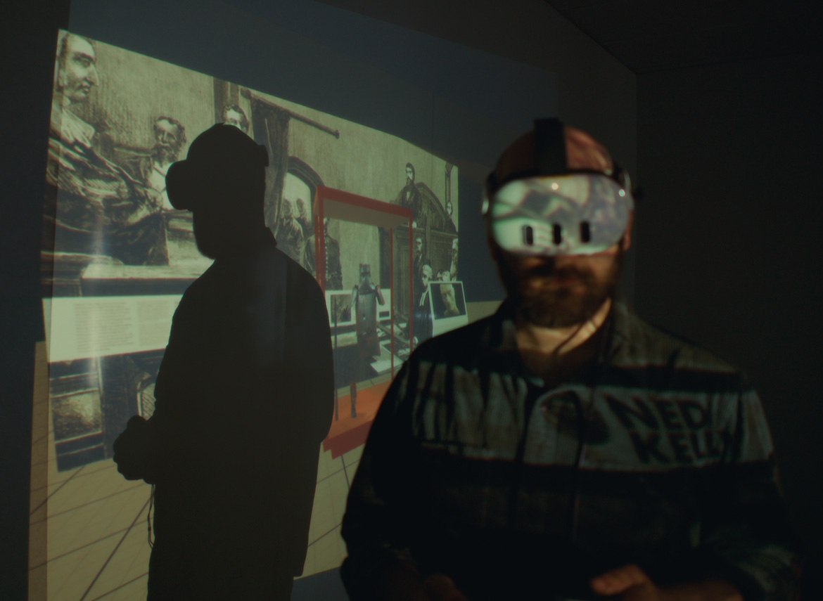 Man wearing VR headset with image of Ned Kelly's armour projected behind him