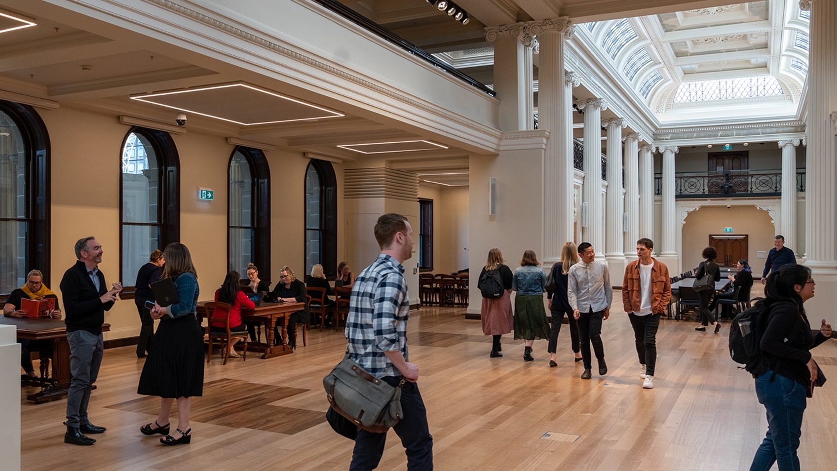 people in public space with pillars and coffered ceiling