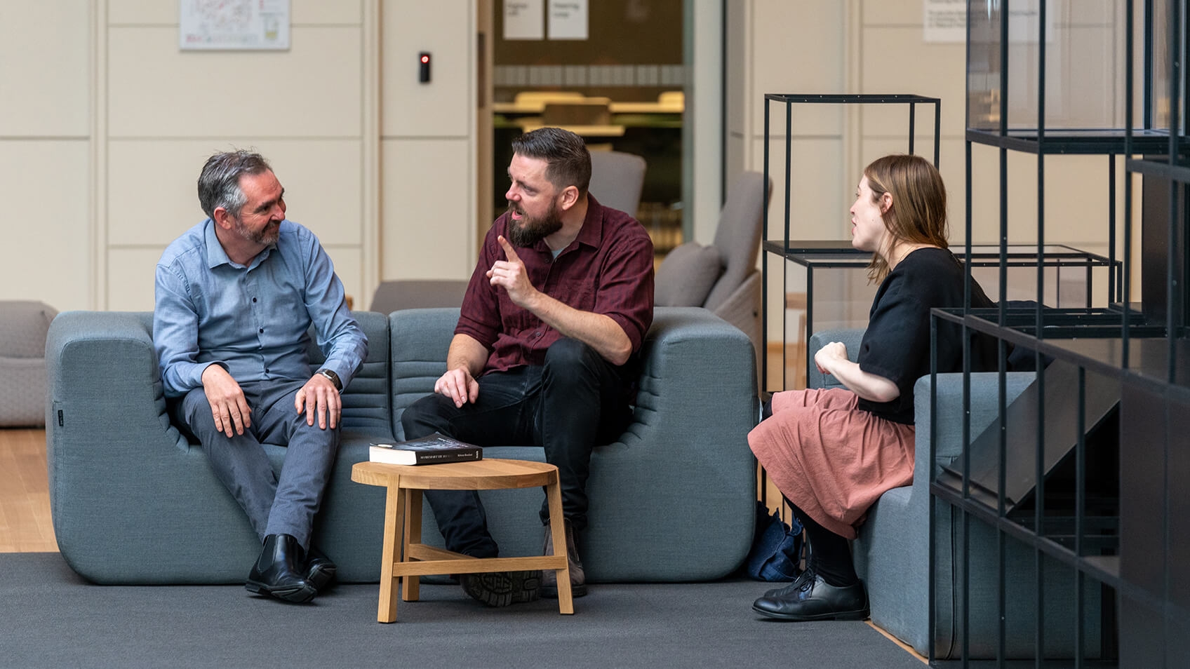 three seated people chatting