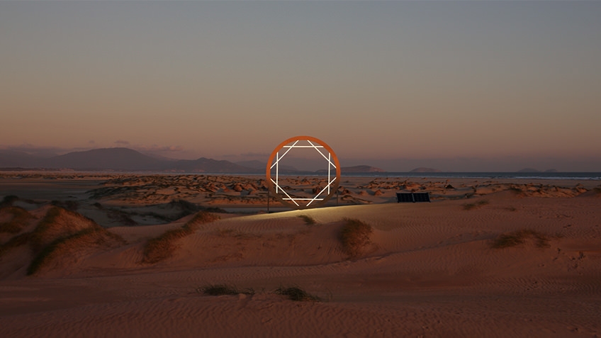 Australian outback coastal scene at dawn or dusk with sand in foreground and low mountains in background