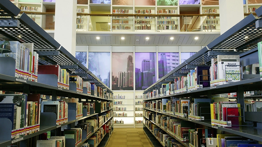 colour photo of library interior with books of shelves and glassed-in mezzanine