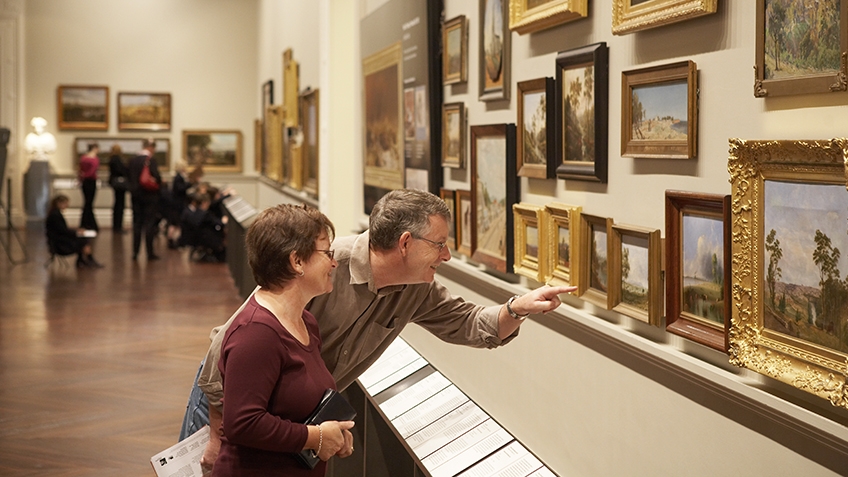 Photograph of visitors in a gallery looking at paintings