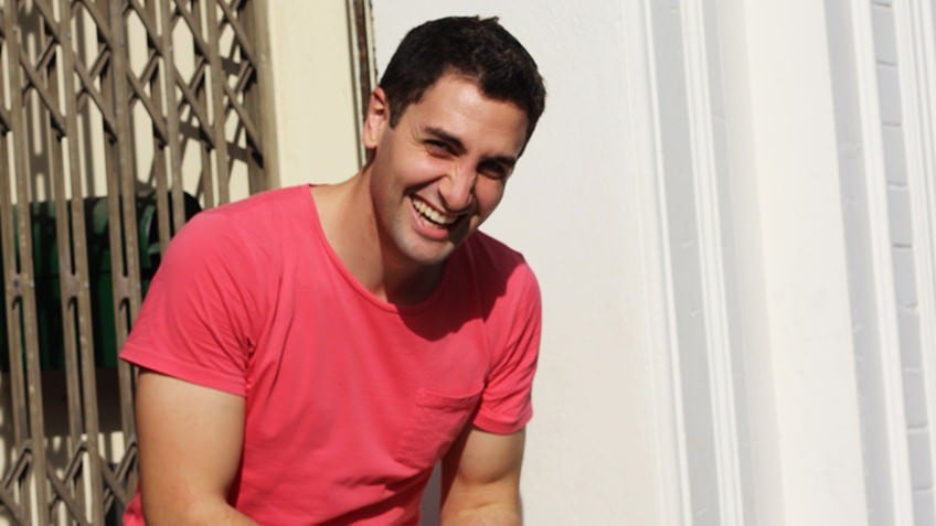 Smiling man with dark hair wearing a red T-shirt