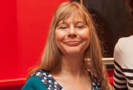woman with blonde hair and blue dress against a red background
