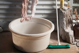 An image of an outdoor area with a bucket, soaps and clothing.