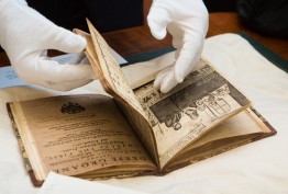 A pair of gloved hands turn the pages of a rare and valuable book