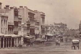 Photograph of Collins Street from Swanston Street, Melbourne, ca. 1872. Shows buildings including Staffordshire House and W. H. Rocke & Co. Several horse and carriages can be seen along the street. 