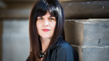 Woman leaning on a wall and looking at the camera