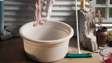 An image of an outdoor area with a bucket, soaps and clothing.