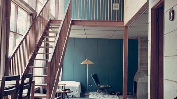 modernist house interior with wooden staircase to mezzanine level from lounge