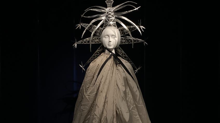 A mannequin wears a striking headress and a floor-length cloak