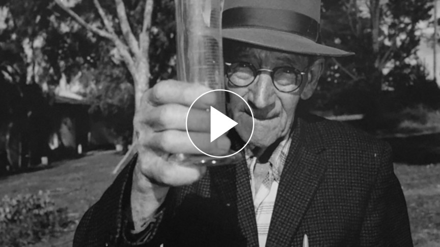 Black and white photo of a man holding up a glass of water