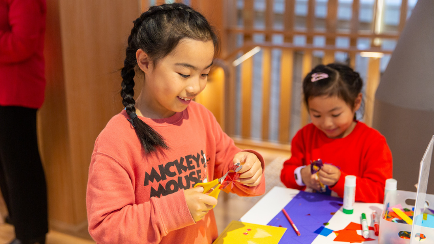 Two young children cutting up bits of paper