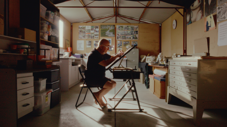 Image featuring artist Joe Monteleone in his studio, working on linocut prints at an angled workstation